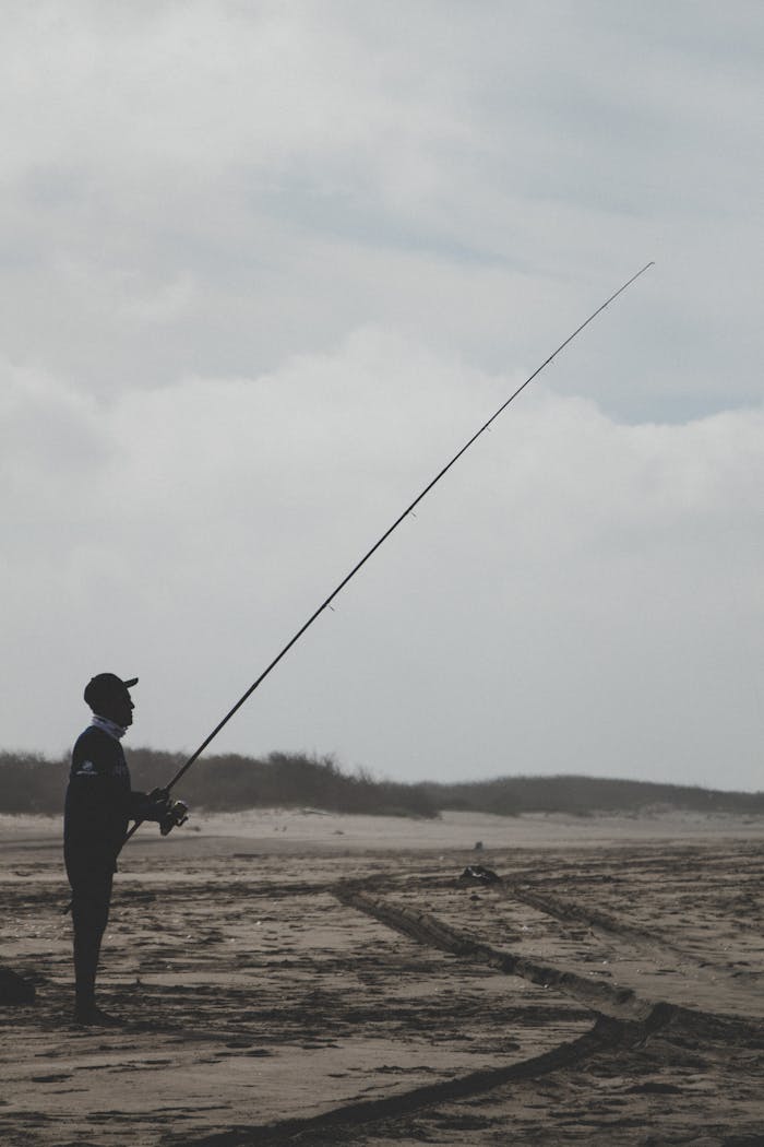 A fisherman silhouetted against the sky, casting his line on Altata Beach, Mexico.